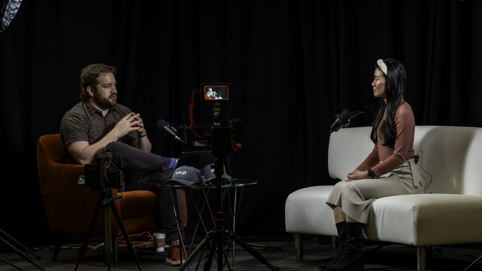 Conor Bronsdon in conversation during a recorded interview, mid-gesture across from a guest under studio lighting.